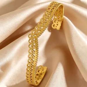 Close-up of a vintage golden stainless steel cuff bracelet with hollow filigree design