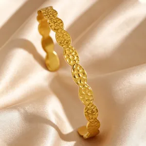 Macro detail of a vintage gold-toned stainless steel hammered texture wavy open bangle