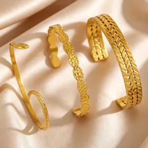 Detailed view of three vintage gold-finished stainless steel textured cuff bracelets