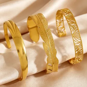 Close-up of vintage golden stainless steel bangles with feather and hollow leaf patterns