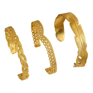 Detail of three vintage gold stainless steel bangles featuring feather and braided designs