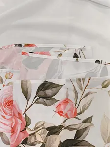 Vista dettagliata dell'elegante stampa floreale rosa su tessuto bianco con cuciture fini.