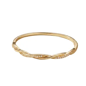Elegant gold-tone intertwined wave bangle with sparkling pavé cubic zirconia accents.