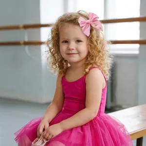 Close-up of a young girl wearing a pink embroidered ballet-themed bow hair clip in a studio