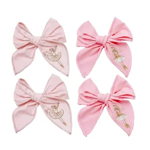 Close-up of handmade pink fabric hair bows featuring delicate embroidered ballet girl
