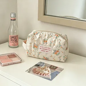 Detail view of a floral quilted makeup bag with zipper closure on a white vanity