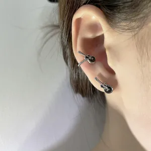 Detail shot showing vintage punk style black guitar ear cuff and earring on ear