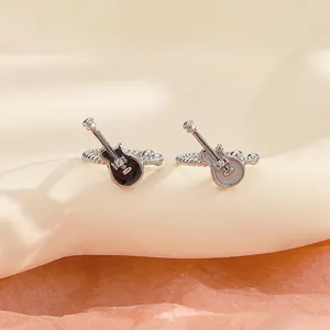 Macro view of black and white guitar-shaped ear cuffs with sparkling crystal accents