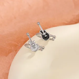 Close-up detail of black and white punk guitar-shaped musical instrument ear clips.