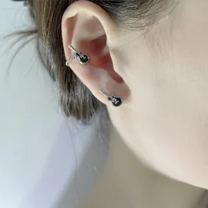 Close-up detail of vintage punk style black guitar ear cuff and stud earring on ear