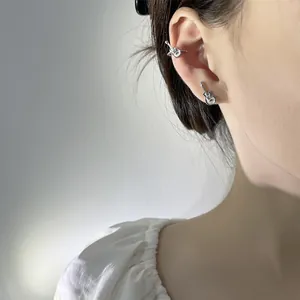 Detailed view of guitar-shaped silver earrings worn on an ear cuff and stud set