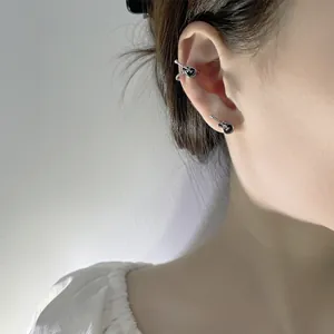 Close-up detail of silver and black guitar-shaped ear cuff and stud set in punk music style