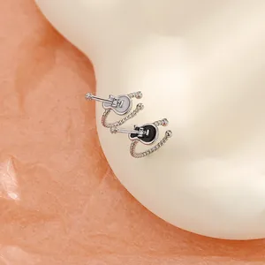 Macro detail view of black and white guitar shaped ear cuffs on a professional model ear