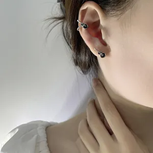 Close-up detail of punk style black guitar ear cuff and stud earring set