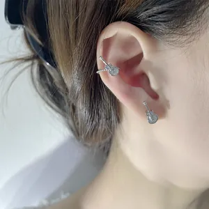 Detailed view of punk style silver guitar ear cuff and stud earring on an ear