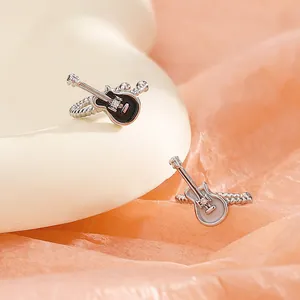 Close-up of black and white guitar-shaped ear cuffs with small crystal details.