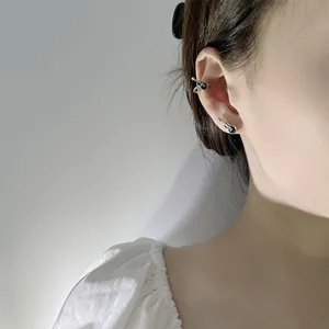Close-up of a model wearing retro black guitar shaped ear clips and silver stud earrings.