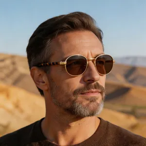 Close-up of classic oval gold metal frame sunglasses worn by a male model
