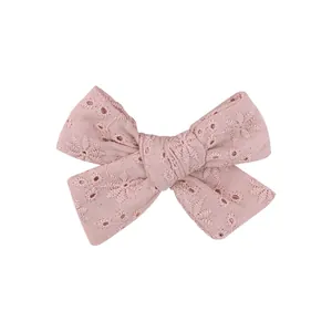 Close-up detail of a pink children's hair clip featuring delicate floral embroidery patterns