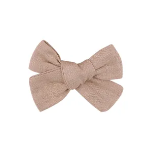 Detail view of a handmade linen fabric bow hair clip in natural beige color for kids