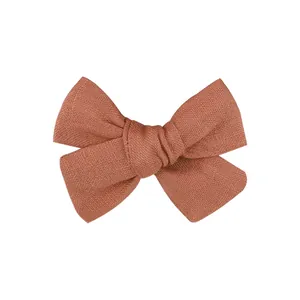 Detailed close-up shot of a handmade rust-colored terracotta linen bow hair clip