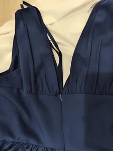 Détail d'une robe élégante bleu marine avec col en V, fermeture éclair et taille plissée