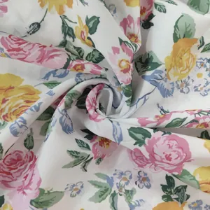 Gros plan d'un tissu de robe blanc avec des imprimés floraux roses et jaunes éclatants