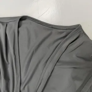 Détail du décolleté en V et de l'épaule plissée d'une robe grise en maille côtelée pour femme