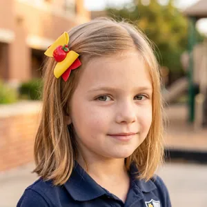 Gros plan d'une fillette portant une barrette nœud jaune et rouge avec décor de pomme