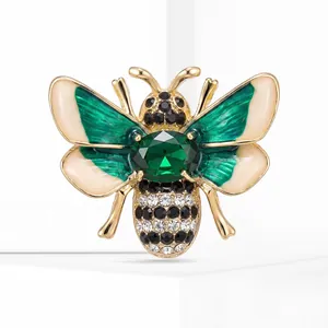 Detailed view of a gold-tone bee brooch with emerald crystal and green enamel wings.