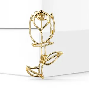Macro view of an elegant golden hollow rose brooch displayed on white minimalist blocks.
