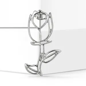 Close-up detail of minimalist silver-tone hollow-out rose flower brooch pin