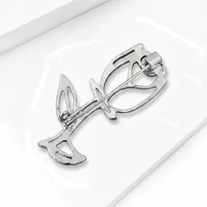 Detailed macro view showing the back safety pin mechanism of a silver hollow rose brooch.