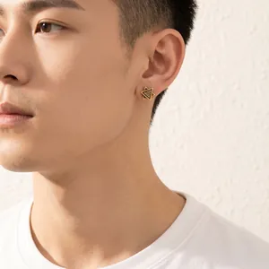 Gold-toned Eye of Providence stud earring worn by a male model against a white wall