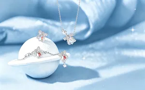 Close-up of silver jewelry set with iridescent star and wing charms on blue silk