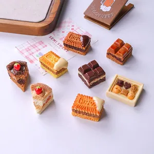 Close-up of realistic miniature food charms including cakes, chocolates, and biscuits.