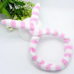 Soft pink and white striped plush headband for skincare and makeup routines.