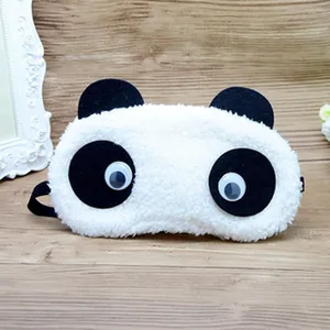 Close-up of a cute white fluffy panda plush sleep mask with black ears and googly eyes.