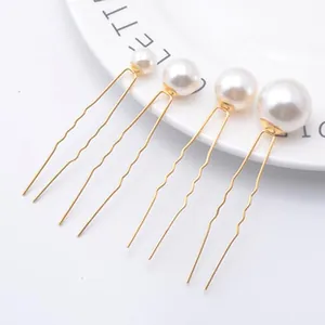 Detailed view of four gold U-shaped hairpins featuring white pearls in graduated sizes