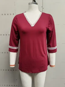 Close-up view of a wine red V-neck T-shirt featuring white lace patchwork design.