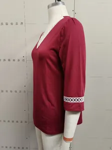 Detail view of a burgundy V-neck top featuring white lace trim on the sleeves and neckline.