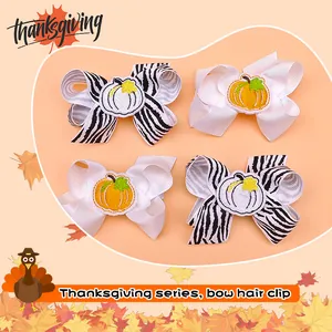 Detailed view of children's embroidered pumpkin bow hair clips for Thanksgiving