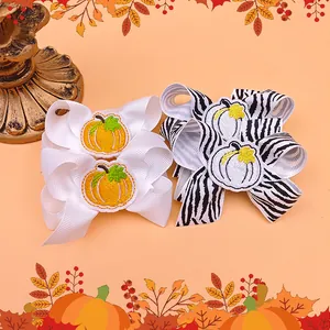 Set of children's embroidered ribbon bow hair clips with festive pumpkin designs.