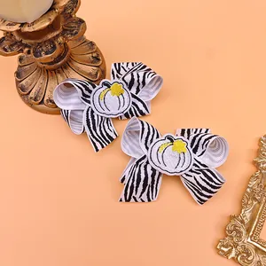 Macro view of zebra print bow hair clips featuring a detailed embroidered pumpkin center