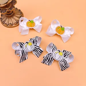 Close-up of children's embroidered pumpkin bow hair clips for Thanksgiving theme