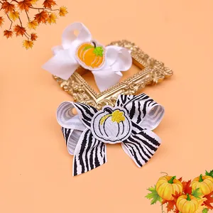 Close-up of white and zebra print hair bows with embroidered pumpkins.