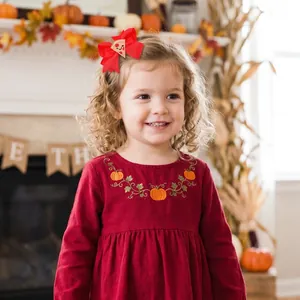 Close-up of a toddler wearing a red embroidered pizza bow hair clip for Thanksgiving