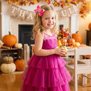 Close-up of pink embroidered pumpkin bow hair clip on a smiling young girl for Thanksgiving