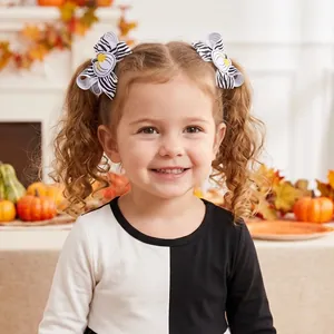 Detailed view of child wearing zebra print pumpkin embroidered bow hair clips