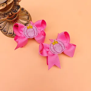Detailed view of pink embroidered bow hair clips with glittery pumpkin design